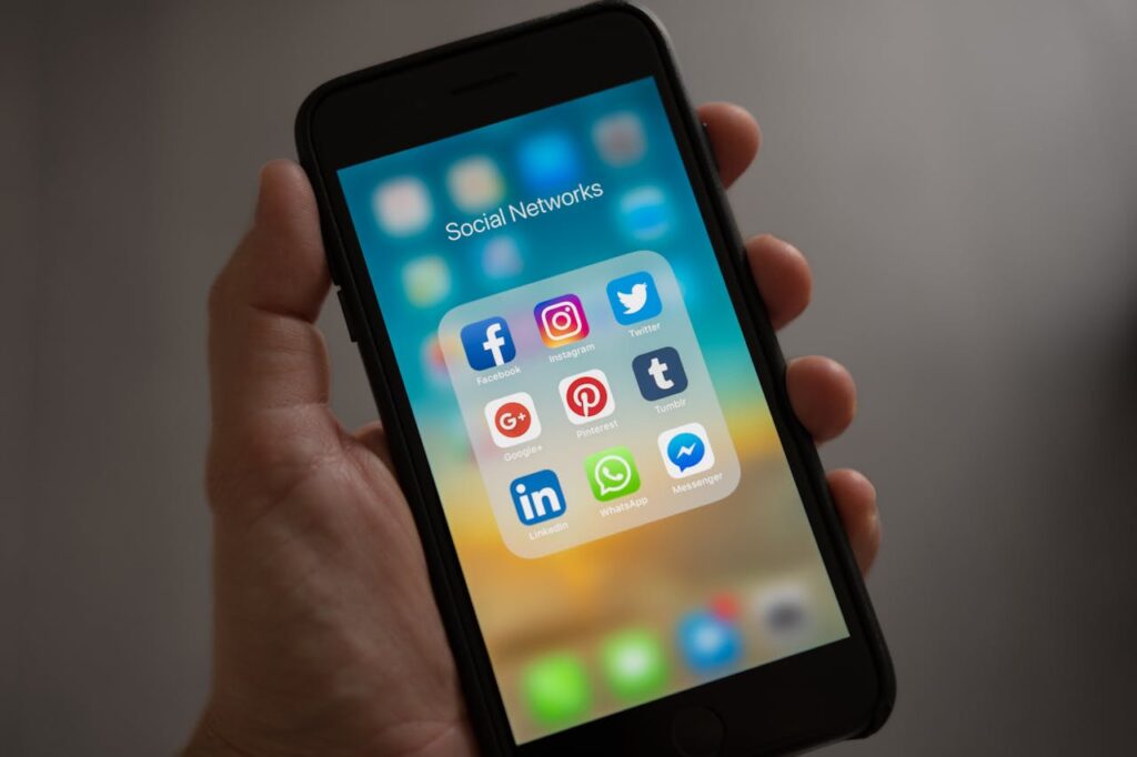 Smartfon z folderem aplikacji społecznościowych, takich jak Facebook, Instagram, Twitter i LinkedIn, jako narzędzie promocji biznesu.