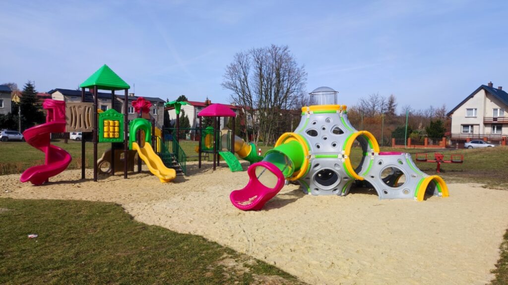 nowoczesny plac zabaw z kolorowymi zjeżdżalniami i modułami wspinaczkowymi na osiedlu