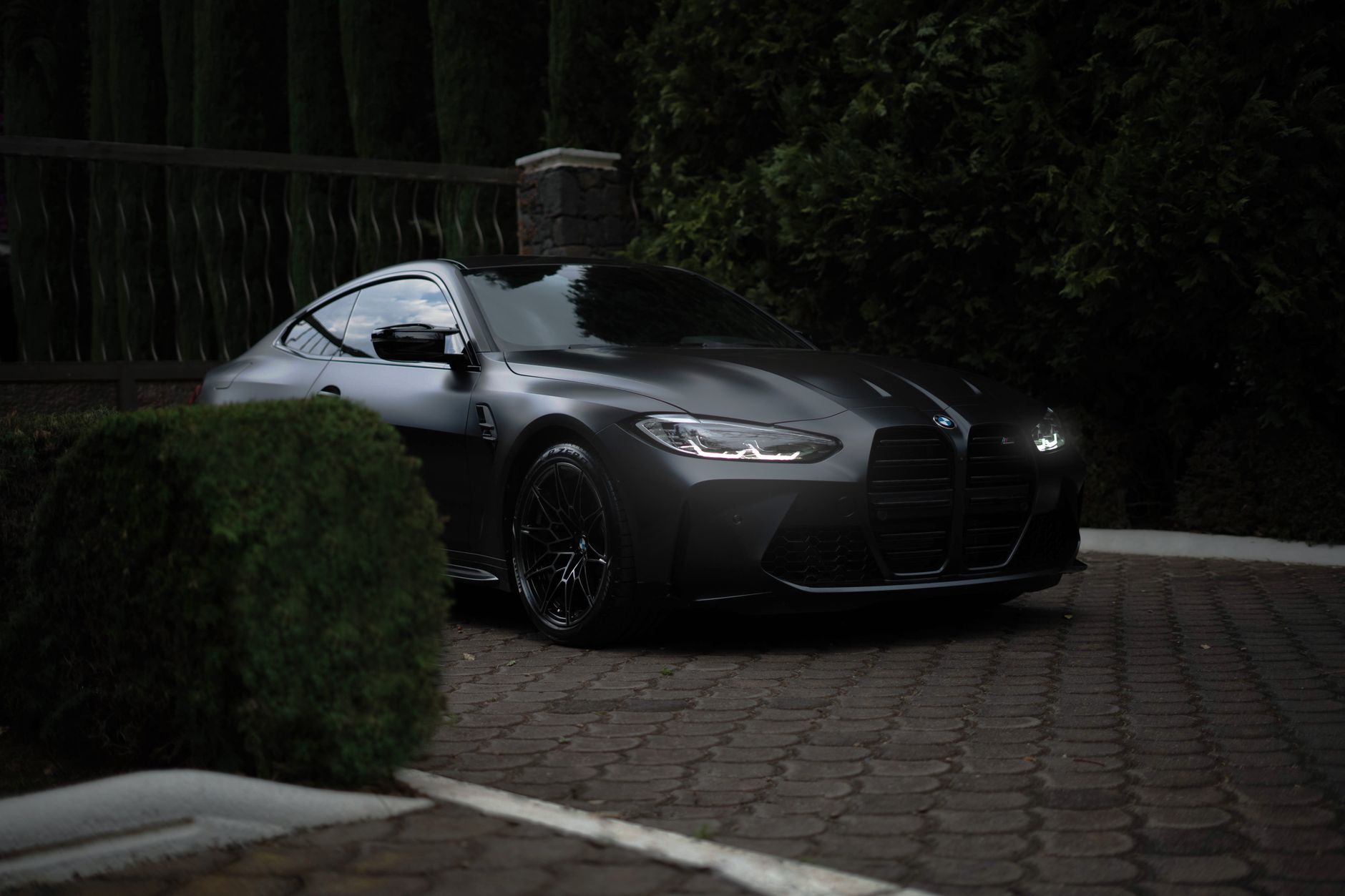 Czarny samochód BMW zaparkowany przed domem